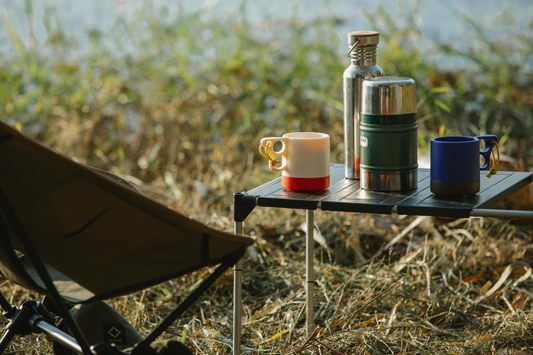 A tumbler, a jar, and two mugs on a camping table