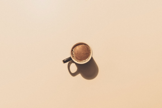  An espresso shot in a mug over a brown background.